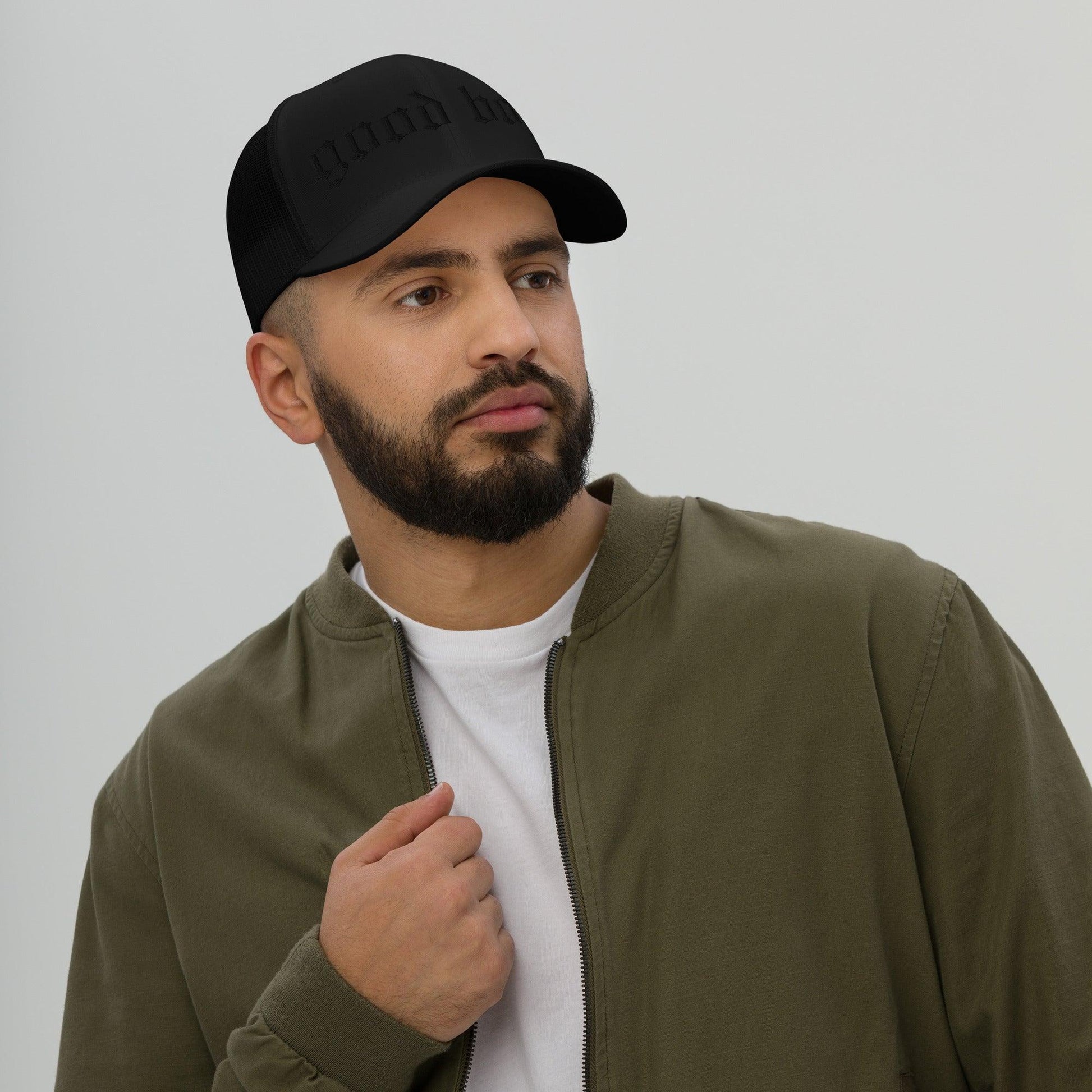 Man wearing Good Boy Trucker Cap in After Midnight black hat with olive green jacket and white shirt